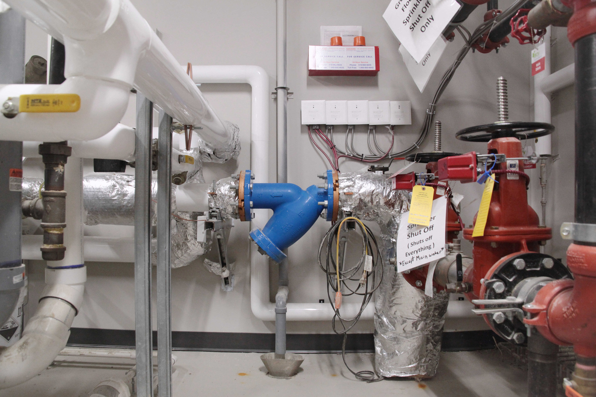 White, red and blue pipes in a boiler room. A plumbing or backflow prevention project by Barrett Mechanical at a multi-unit residential building or retirement home in Strathroy or St. Thomas.