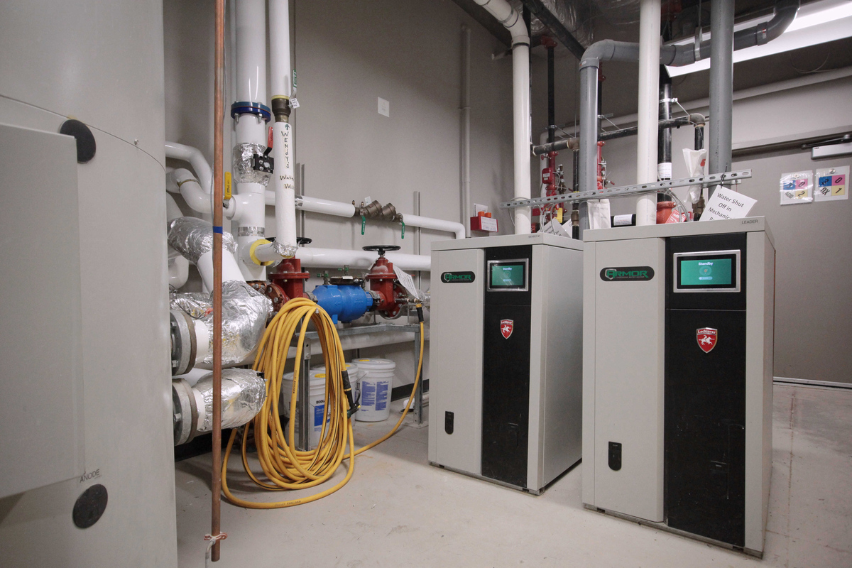 White, red and blue pipes in a boiler room. A plumbing or backflow prevention project by Barrett Mechanical at a multi-unit residential building or retirement home in Strathroy or St. Thomas.